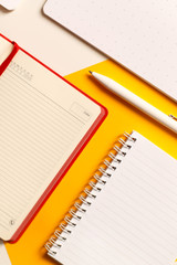 Business composition. Red open diary on a yellow background with notebooks and a white pen close-up. View from above. Flat lay.