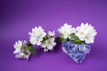 Fototapeta na wymiar Hand made soaps on the purple background. White flowers on the natural cosmetic. Small business
