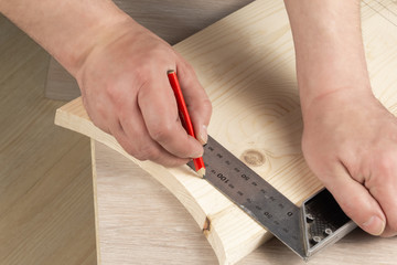 The craftsman marks the wooden board with a ruler and pencil. Carpentry workshop. Work carpenter