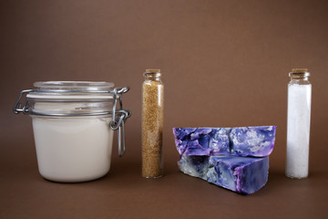 Hand made soaps, body cream or lotion, salt and sugar on the brown background. Natural cosmetics. Small business. Copy space.