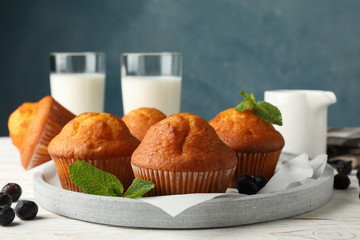Composition with muffins and milk on white wooden background