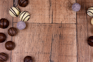 Fototapeta na wymiar Chocolate pralines frame top view stock images. Chocolate candies on a wooden background. Chocolate frame top view. Chocolate pralines on a wooden table stock images. Border of different candies photo
