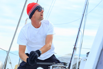 Happy sailor dressed in casual wear and sunglasses on a yacht. Norwegian fishing boat.