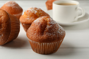 Delicious muffins and cocoa drink on white wooden background