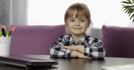 Fototapeta premium Girl sitting on table at home. Studying online homework. Distance education
