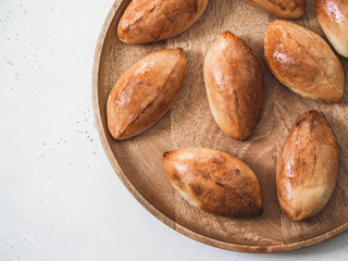 Russian yeast portioned pies stuffed on wooden dish. Top view