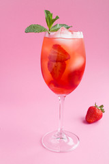 Cocktail drink with strawberry and ice in a glass on the pink  background. Location vertical. Closeup.