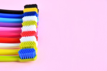 Row of bright colorful toothbrushes with selective focus on pink background. Healthy teeth. Toothbrush for daily oral care