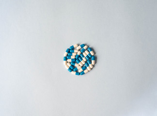 Medical therapeutic dissolving capsules of white and blue colors in the shape of circle on a blue background. Top view. Copy space