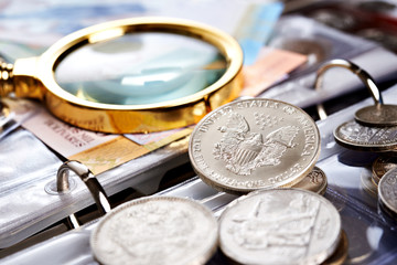 Silver dollar and numismatic coins with magnifying glass