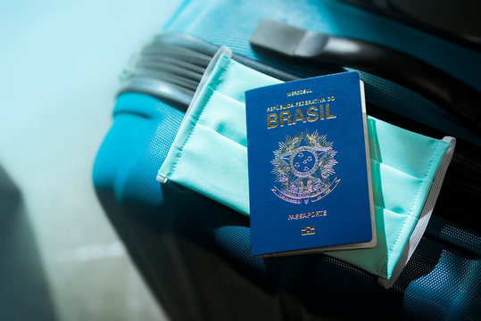 Mala de viagem, passaporte brasileiro e m&aacute;scara de prote&ccedil;&atilde;o. A proibi&ccedil;&atilde;o e as novas medidas de viajar durante a epidemia do coronav&iacute;rus.