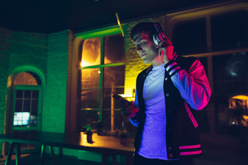 Enjoying music. Cinematic portrait of stylish man in neon lighted interior. Toned like cinema...