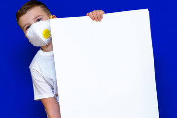 Close up Portrait of caucasian boy in a protective mask respirator holds a blank sheet of paper on...