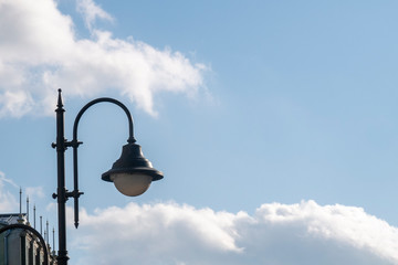 Street lantern against blue sky with white clouds. Background image with copy space.