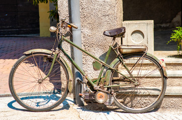Naklejka na ściany i meble a vintage green bicycle with engine, leaning against the wall