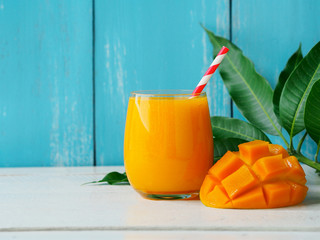 Mango juice served with fresh ripe mango sliced for the summer drinks concept. Copy space on the left side of the picture.