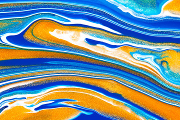 Fluid art texture. Background with abstract mixing paint effect. Liquid acrylic picture that flows and splashes. Mixed paints for baner or wallpaper. Blue, golden and white overflowing colors