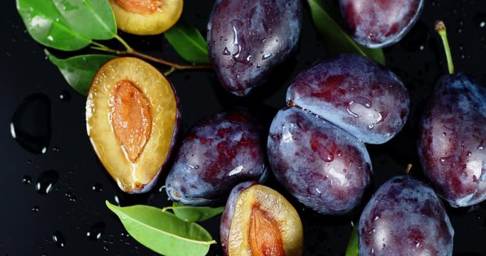Whole and slices plum with leaves slowly rotate.