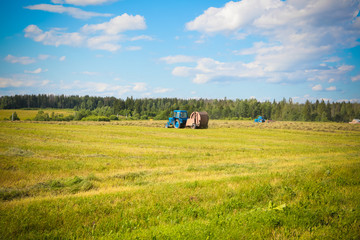 hay harvesting by blue tractor.