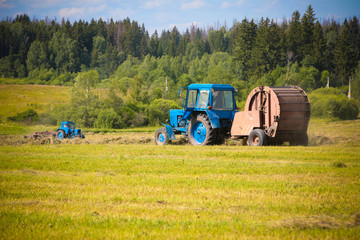 Obraz premium hay harvesting by blue tractor.