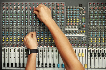 male sound engineer hands working on audio mixing console. toned