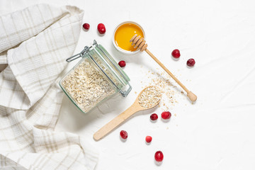 Healthy breakfast concept. Organic oat flakes, cranberries and honey on white concrete background top view. Healthy lifestyle concept.