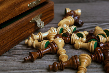 scattered chess pieces with chessboard on a wooden background