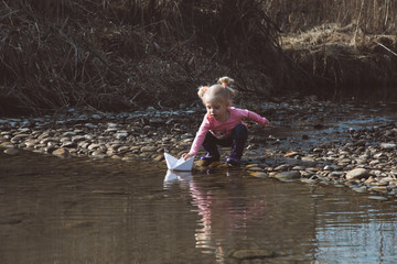 Little girl launches paper boats 