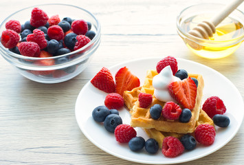 Belgian waffles with fresh fruit on wooden background