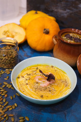 Autumn food - pumpkin soup with cream, shrimps and seeds in bowls on table. Served for dinner. View from above