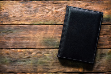 Closed book with leather cover on brown flat lay table background with copy space.