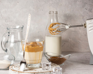Dalgon's whipped coffee in a glass Cup on a white wooden background. Next to the ingredients for making a Korean refreshing coffee drink.