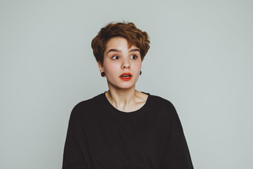 The girl stands on a white background and shows emotions