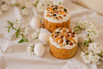 Delicious festive Easter cake, Easter eggs and blossoming twigs of apple tree on linen light background