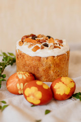 Easter cake and red eggs with twigs leaves on linen light  background, easter celebration concept. Top view.