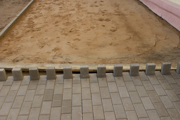 The process of laying paving slabs on yellow sand.