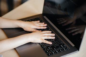 Hands of a child close-up on the laptop keyboard. Distance learning. Stay at home