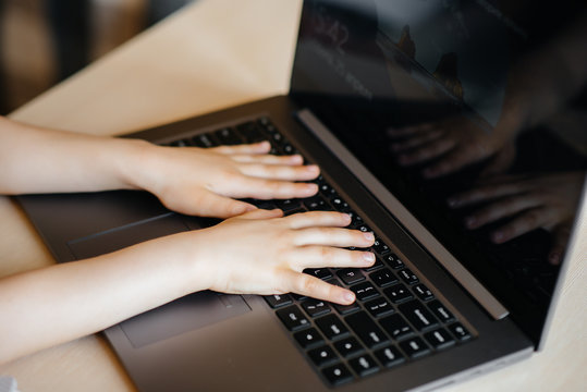 Hands of a child close-up on the laptop keyboard. Distance learning. Stay at home
