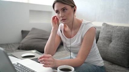 Technology, video conference, virtual event concept - happy young woman in headphones working and making a video call with laptop computer at home during coronavirus COVID19 pandemic quarantine. 