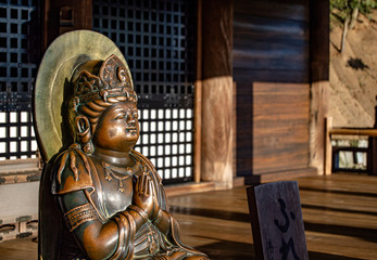 Kyoto, Japan - May 04, 2019: Closeup macro detail of a crowned buddha in the Namaskara prayer position. Kiyomizu-Dera Temple, Higashiyama. Travel and religion. © Carmen Romero
