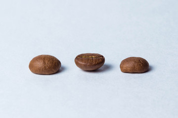 Fototapeta premium Three coffee beans stand in a row on a white background