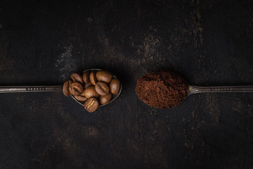 two spoons with coffee on a black background. One spoon with coffee beans. Second spoon with ground...