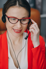 Woman receptionist wear headset consulting customer looking at computer talking with client in online computer chat, young female helpline operator secretary make conference video call.