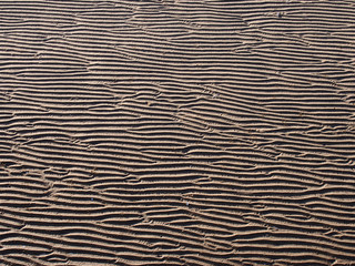 A full frame beach background with wavy pattered surface formed by water on the wet sand and shadow