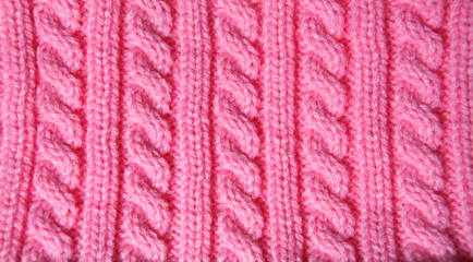 Pink background of hand-knitted pattern on the spokes-pigtail.