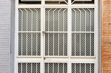 Large white painted iron gate with a grid and reinforcing wire mesh lattice in a facade house from Seville, Spain