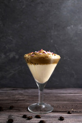 Dalgona coffee with sprinkling with hearts in a glass glass on a wooden background, latte on the contrary with coffee beans, save space.