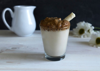 close-up of cooked home Dalgona Coffee with waffle roll, the Korean coffee drink on wooden background.