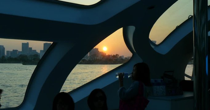 Japanese woman drinks bottled water in Odaiba's sunset, Tokyo, Japan. Futuristic boat perspective 4K