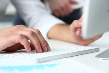 Male arms in suit typing on silver keyboard using computer pc